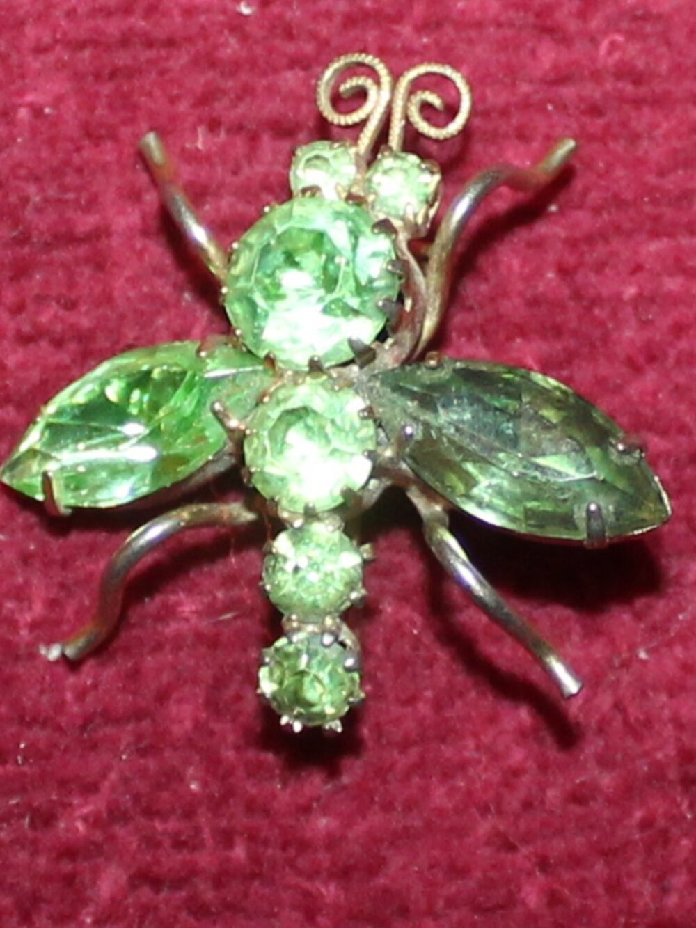 Vintage gold tone bee brooch featuring green rhinestone crystals